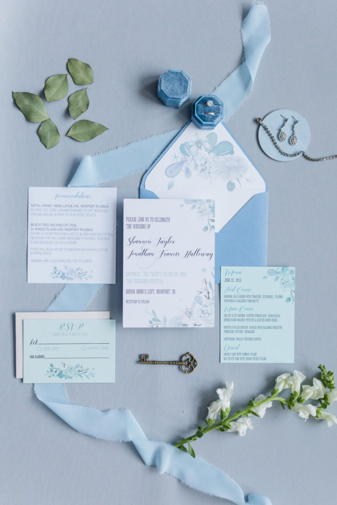 Blue and turquoise floral wedding stationery suite with jewelry and leaves.