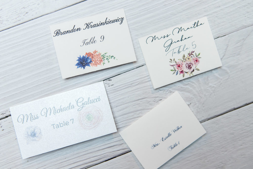 Wedding stationery escort cards in four different styles.