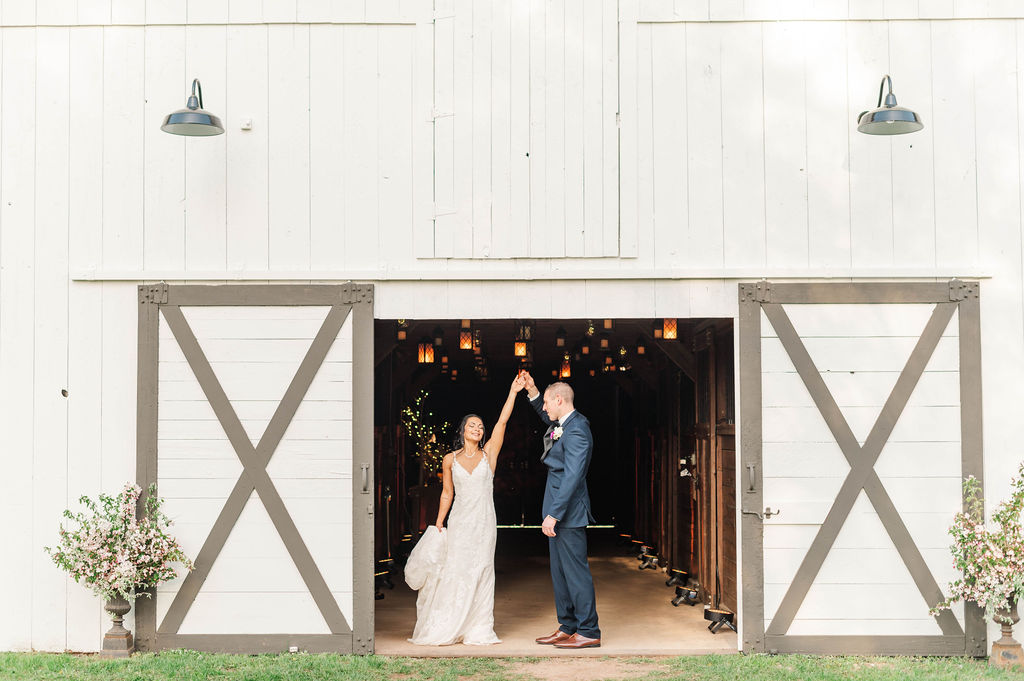 Newly married couple in front of barn decorated for wedding venue.