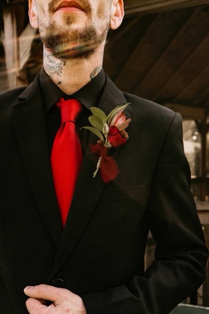 Groom with black suit, red tie, and red boutonniere.