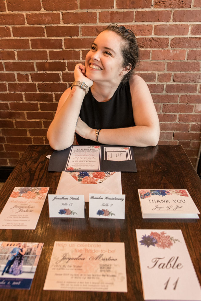 Lauren, custom stationery designer, sitting at her table with stationery examples. 