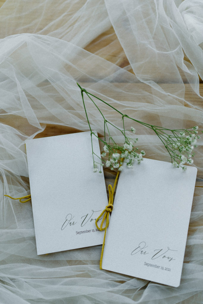 Hand-stitched white vow books with "our vows" written on them.