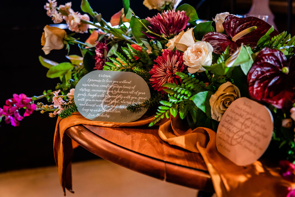 Rounded vow cards displayed with a flower arrangement