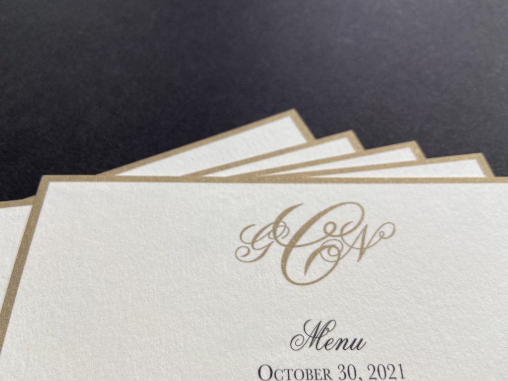 Stack of wedding invitations printed with gold border